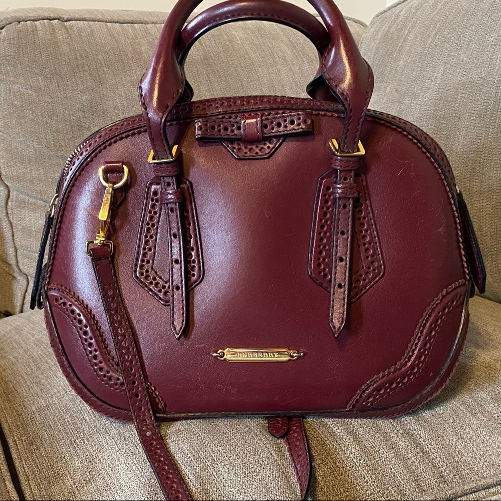 Authentic burgundy Burberry bowler bag with shoulder strap.